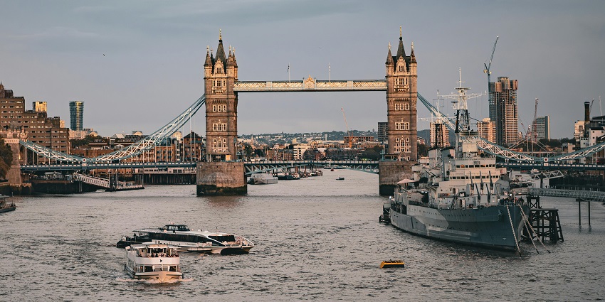 London skyline glowing at sunset with boats moored along the River Thames.