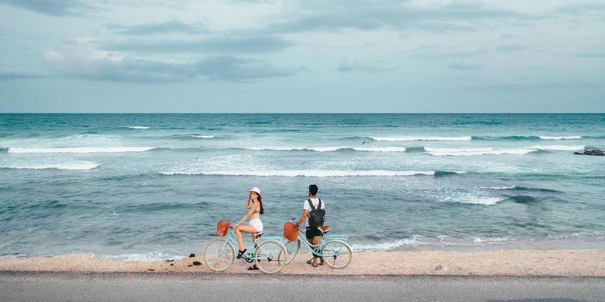 Couples riding bicycles along a sunny beachside path in Kuta and Legian.
