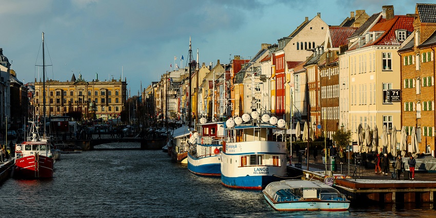 Vibrant boats docked by colorful buildings near Nyhavn Canal, charming places to visit near Scotland.