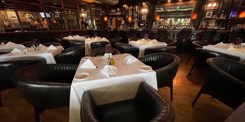 Interior of Capri Italian Restaurant with cosy lighting, floor, and neatly set tables.