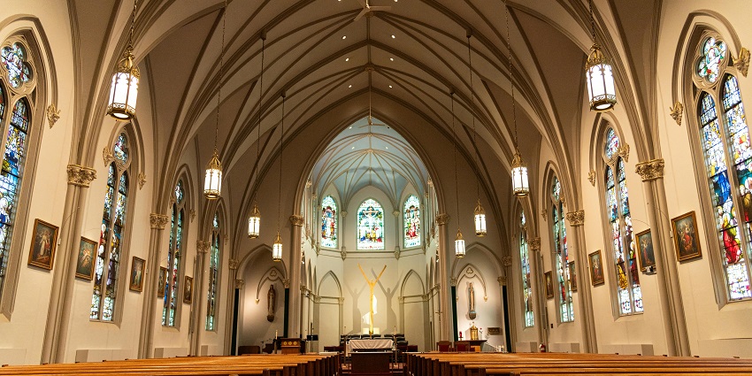 Interior of a small chapel with stained glass, simple icons, and an arched ceiling.