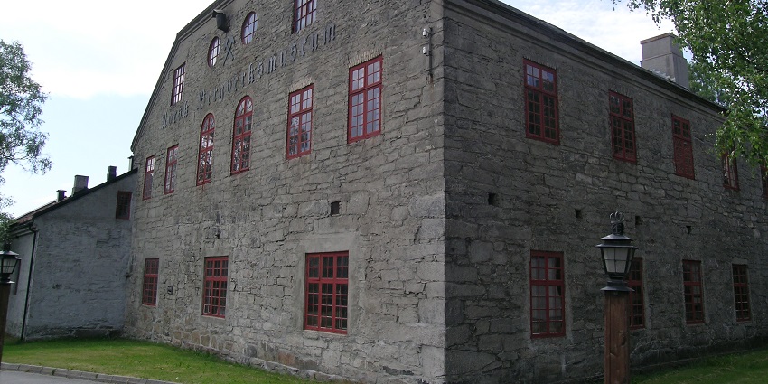 Front view of the Norwegian Mining Museum building with stone walls and arched windows.