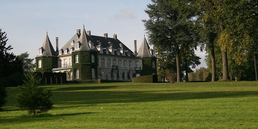 Lush green lawns and trees around Domaine Solvay château in La Hulpe, Belgium.