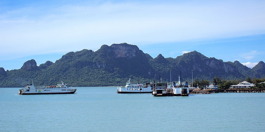 Don Sak Pier with boats, distant buildings, and green hills – places to visit near Koh Samui.