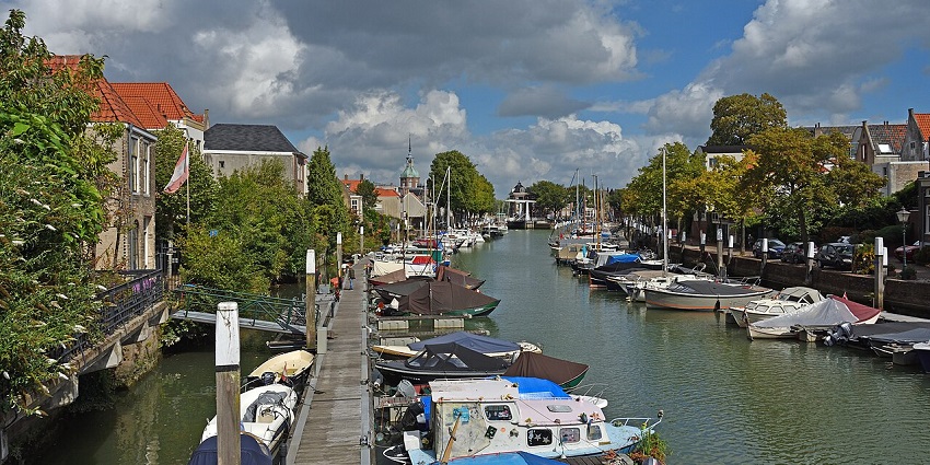 Dordrecht with multiple boats parked in the canal, and buildings on both sides, one of the best places to visit near Rotterdam.