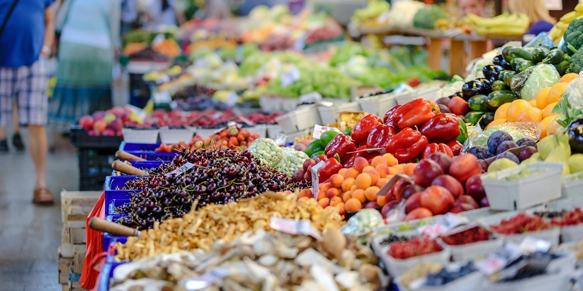 Outdoor view of Woodlands Farmers’ Market with stalls, tents, and people browsing.