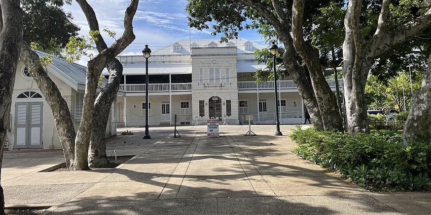 Queen’s Park in Bridgetown with a distant white architectural building and green trees.
