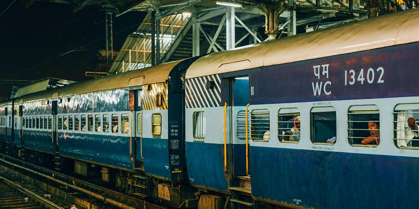 A train at a railway station platform under soft ambient lighting, awaiting passengers.
