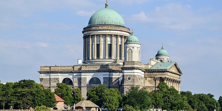 Grand Esztergom Basilica with domed roof and classical architecture under blue sky.