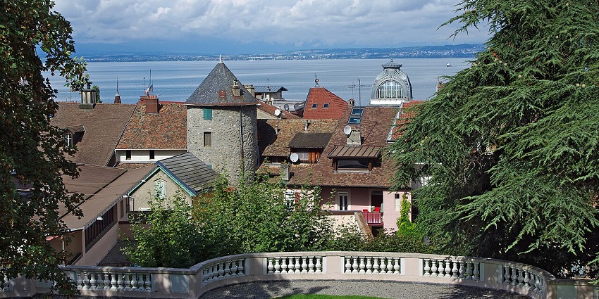 Scenic lakeside view of Évian-Les-Bains town with calm water and mountains.