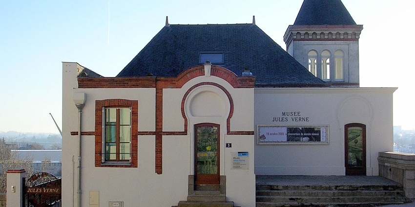 White building with a blue roof, featuring arched windows with a small entrance.