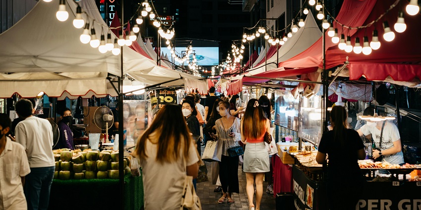 Bustling night market in Pai with colorful shops, bright street lights, and lively crowds.