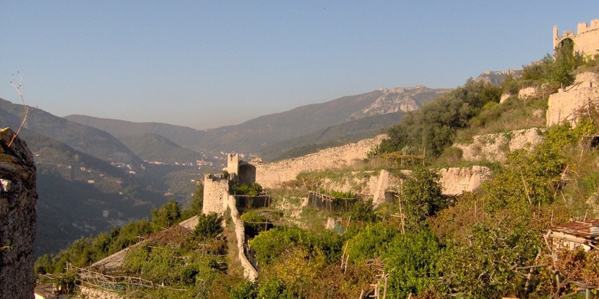 Stone walls and terraced hillside of San Nicola de Thoro-Plano with hills in the distance.