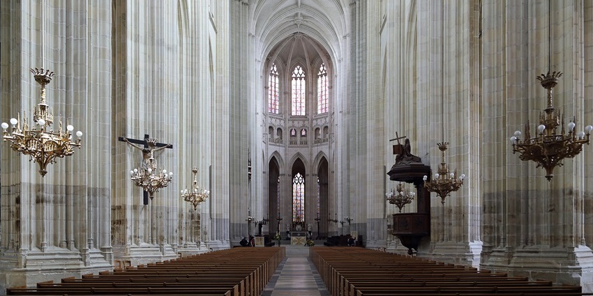 High rise white cathedral featuring high arches and numerous large, ornate chandeliers.