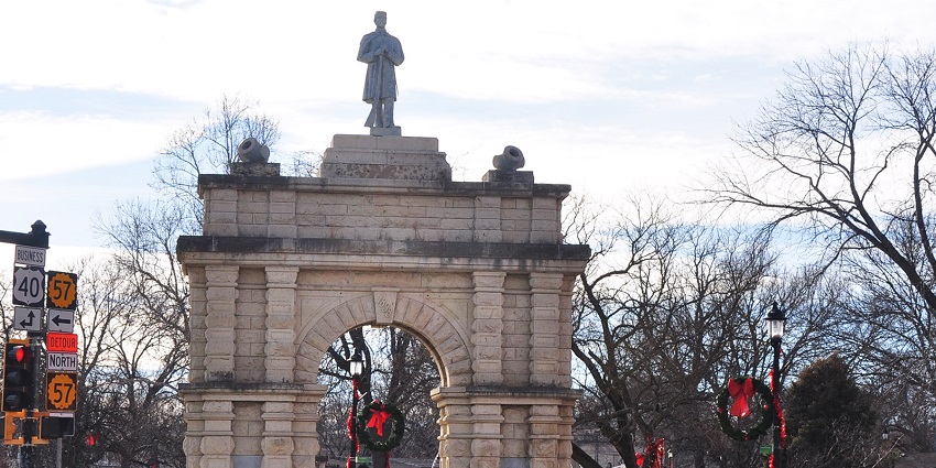 Stone memorial arch with soldier statue on top, located in Heritage Park, Junction City.
