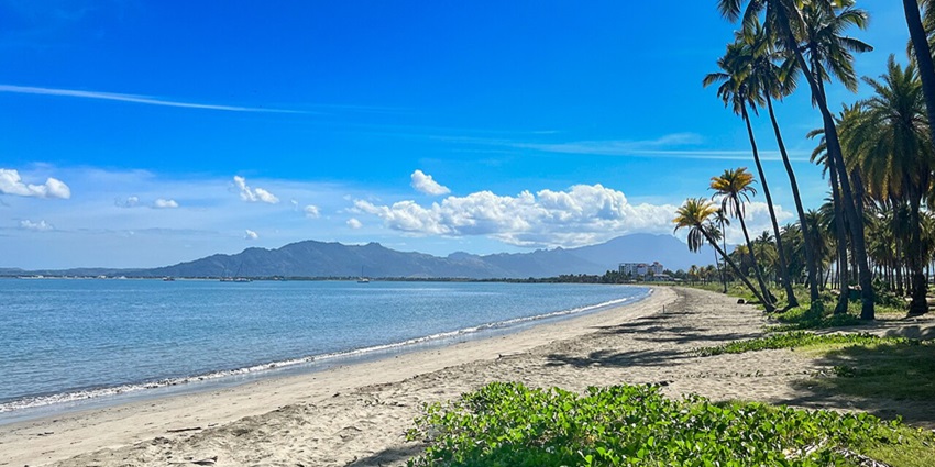Tropical beach in Fiji with clear blue water and white sand under sunny skies.