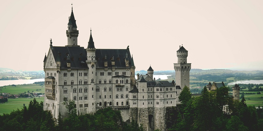The grand structure of Neuschwanstein Castle stands on a hill covered in greenery in Germany.
