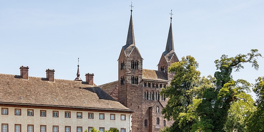 West façade of Corvey Abbey in Höxter, Germany, with twin towers and surrounding greenery.
