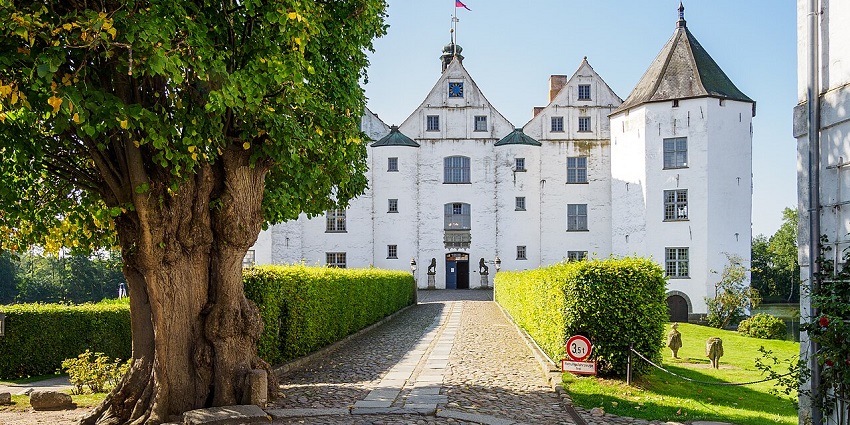 White Renaissance-style castle with twin towers, a cobbled path, amongst the top places to visit near Hamburg.