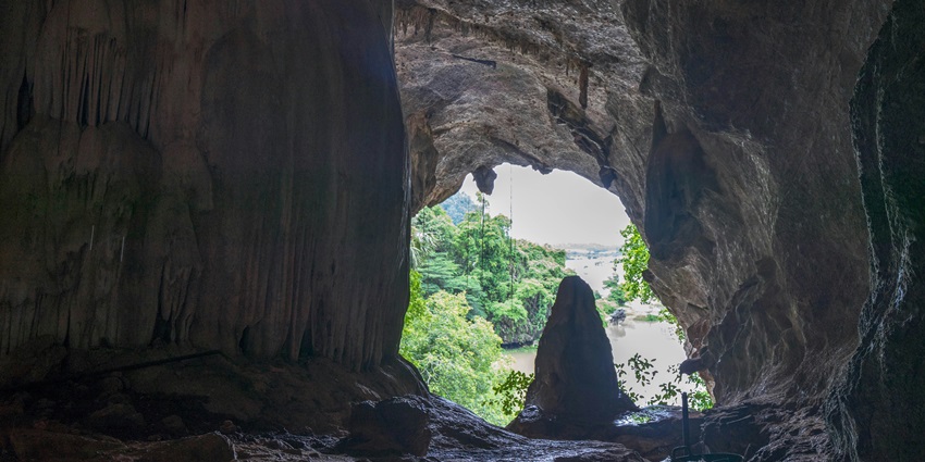 A dramatic vertical cave with sunlight streaming down into the deep chamber below.