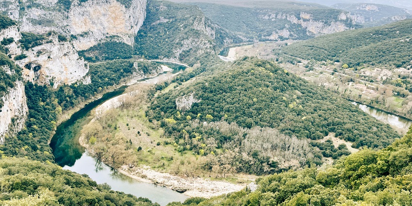 Dramatic limestone cliffs and a winding river cutting through lush green valleys.