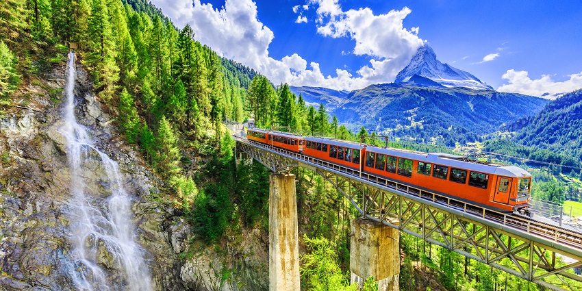 Tourist train at Gornergrat with breathtaking snow-covered mountains and waterfall views, scenic places to visit near Zermatt.