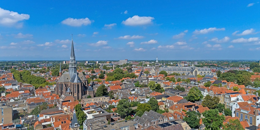Gouda in the Netherlands from above with unique architectural buildings, orange roofs, and trees.