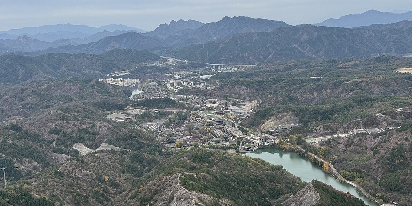 Gubei Water Town is nestled below forested hills, with the Simatai Great Wall in the distance.
