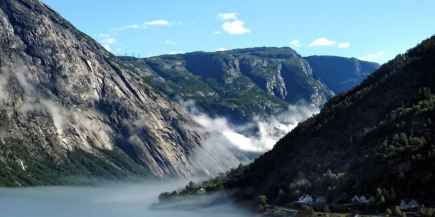Aerial view of Hardangerfjord with misty clouds, scenic shores, and buildings, stunning places to visit near Bergen.
