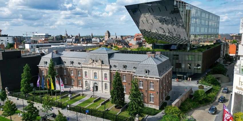 Modern glass building of Hasselt’s new city hall under a partly cloudy sky.