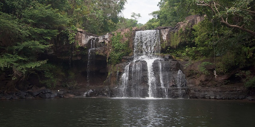 Koh Kut waterfall in Thailand, with water falling into a water body of the lake and greenery.