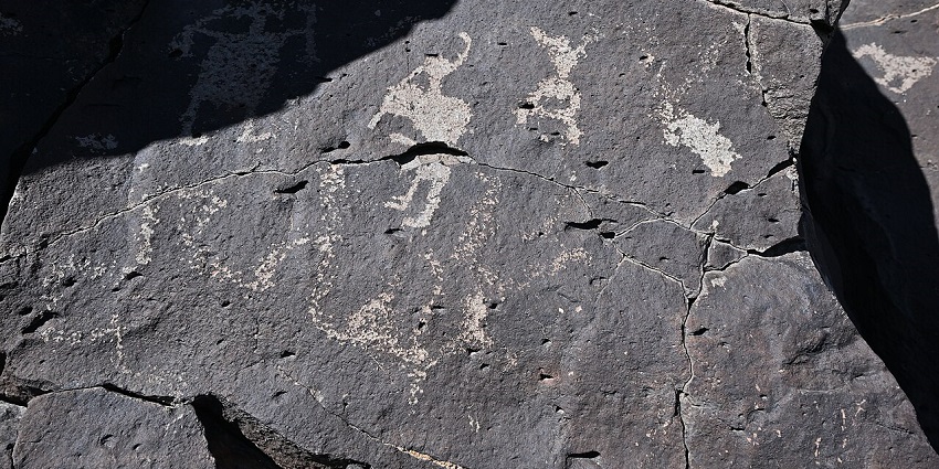 Petroglyphs carved on a stone with unique carvings and a shadow covering half of the rock.