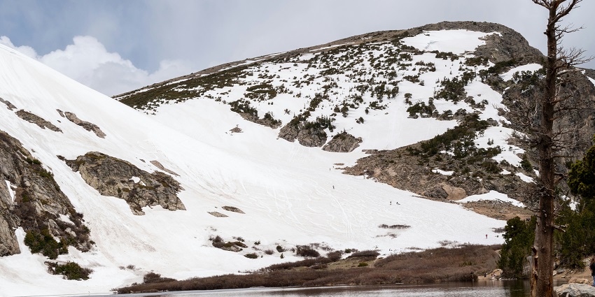 Idaho Springs with snow-covered mountains and a calm lake in a peaceful winter setting.