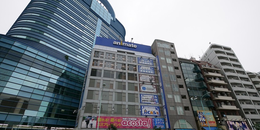 Animate Ikebukuro building with anime shops and signs, surrounded by high-rise structures.