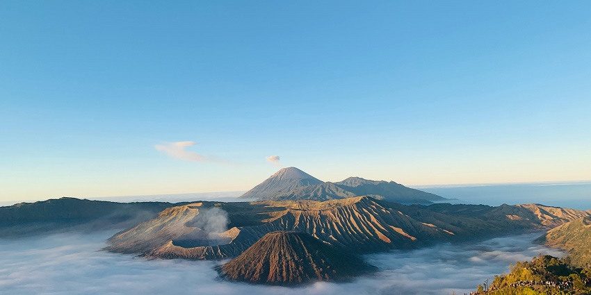 Mount Bromo with volcanic landscape and mist rising in the surface during sunrise.
