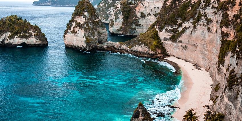 Bali beach with gentle waves, palm trees, and a peaceful sandy shoreline.
