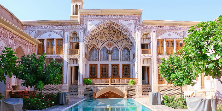 Historic courtyard with a central pool surrounded by traditional Persian architecture in Kashan, Iran.
