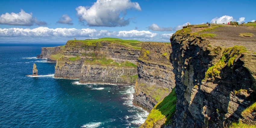 Stunning Cliffs of Moher with green cliffs and waves, one of the places to visit near Scotland.