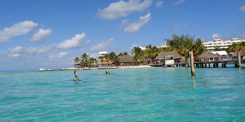 Isla Mujeres island with clear blue water, sandy beaches, and lush greenery.