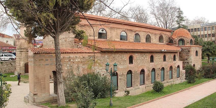 A historic stone building with arched windows and red-tiled roofs, surrounded by trees, amongst the top places to visit near Istanbul.