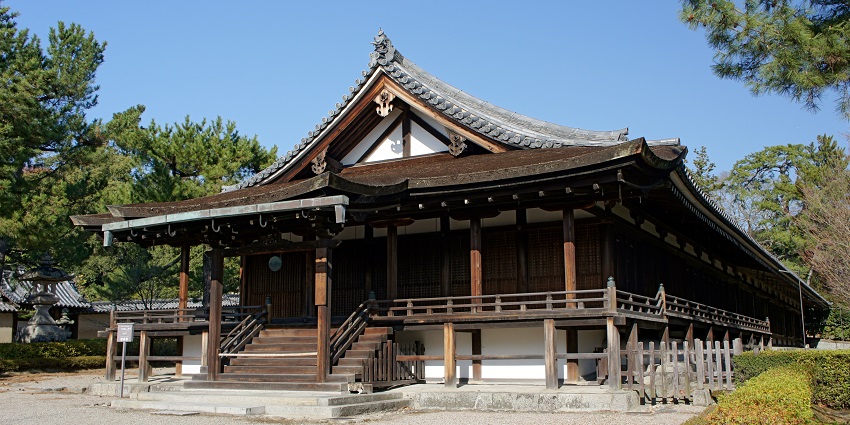 Historic wooden pagoda at Hōryū‑ji Temple in Japan, surrounded by trees and clear skies.