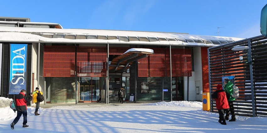 People heading into the snow-covered Siida Museum, with thick snow blanketing the ground.