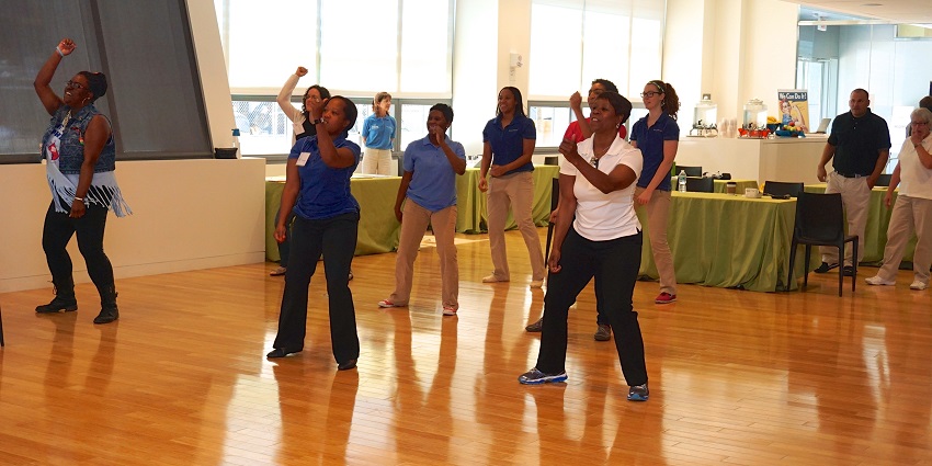 Indoor fitness workshop at Capital Pride event with attendees engaged in group exercises.