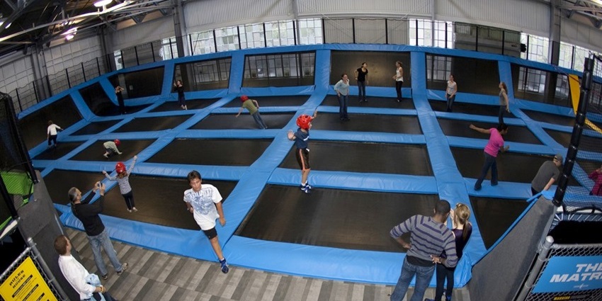 Indoor trampoline park with kids jumping on the trampoline and kids wearing safety gears