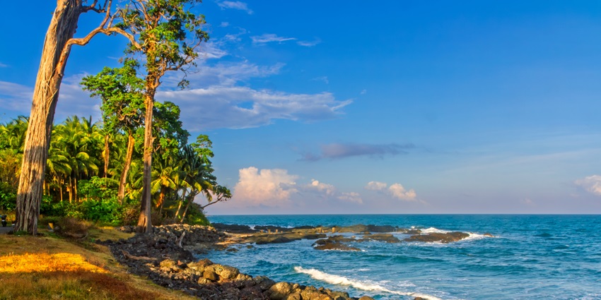 Kala Pathar Beach on Andaman Island, India, with lush trees, rocky shores, and serene blue waves