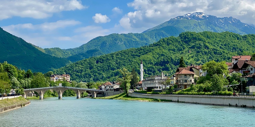 Konjic with a wide water body of a river and buildings is surrounded by lush green hills, one of the places to visit near Sarajevo.