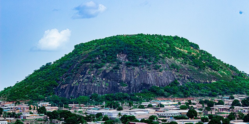 Green hilltop of Mont Korhogo with rocky patches, overlooking buildings, amongst the best places to visit in Ivory Coast.