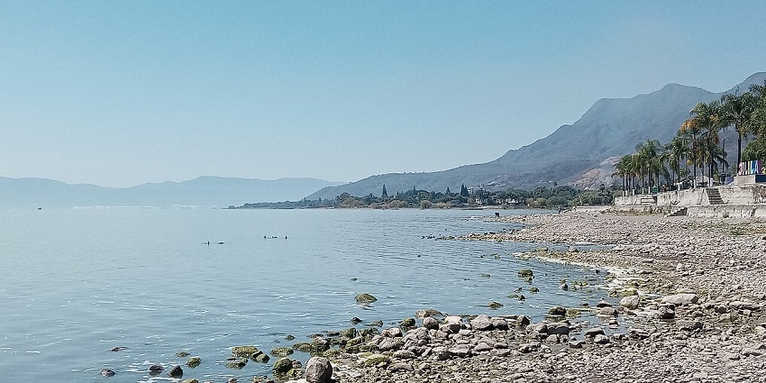 Peaceful view of Lake Chapala from Ajijic with a stony shoreline and mountain, one of the best places to visit near Guadalajara.