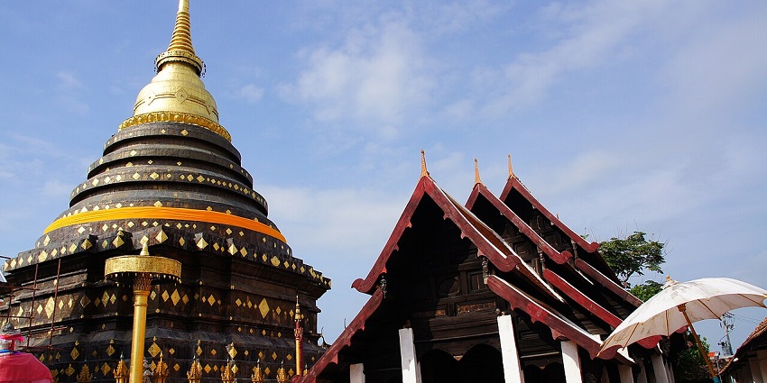 Grand entrance of Wat Phra That Lampang Luang in Lampang with visitors on the staircase.