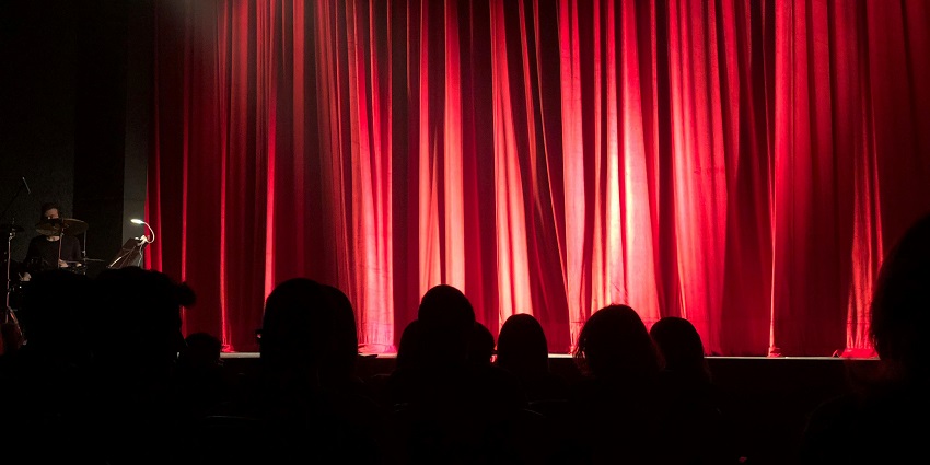 Stage at Orlando Improv Comedy Club with red curtain and spotlight setup in a dim interior.
